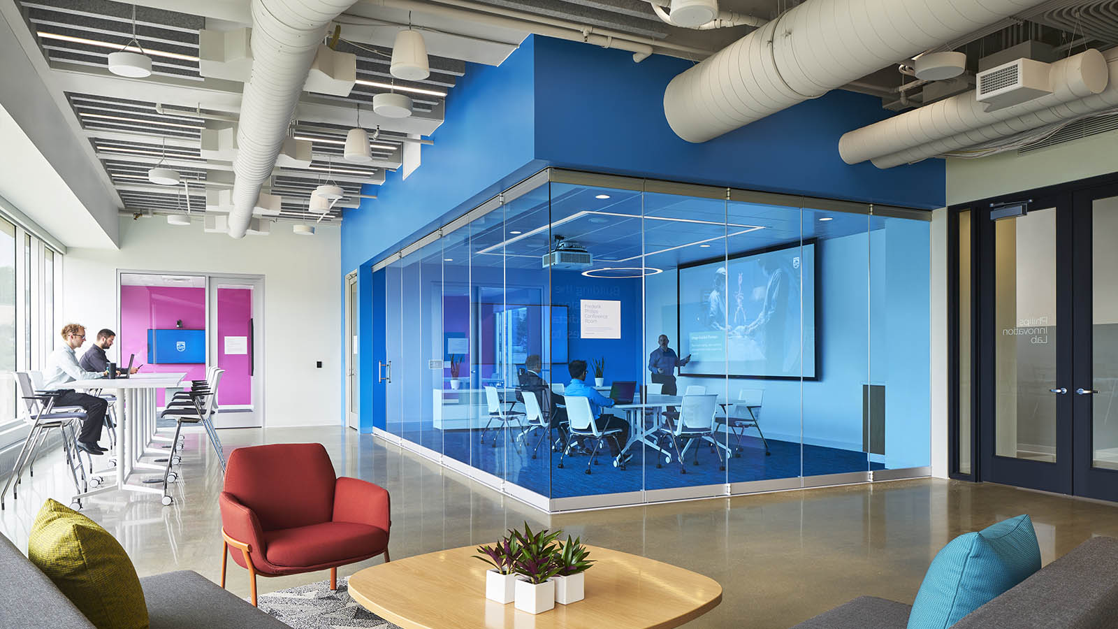 A photograph of a meeting room with blue glass and signage on the doors