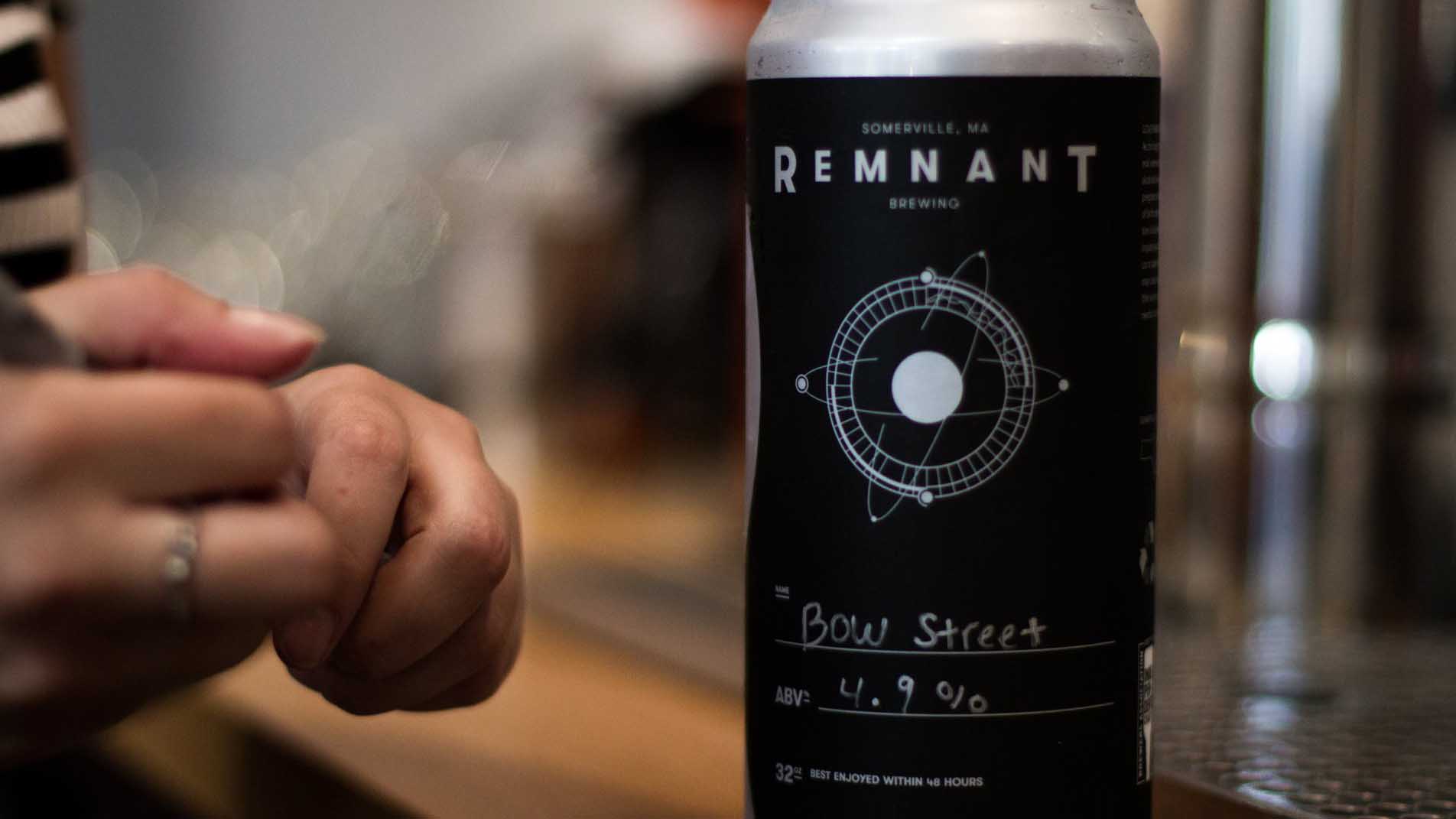 A photograph of a beer can with a black label. there is typography and a drawing of an atom on the label. Design made in Adobe Illustrator.